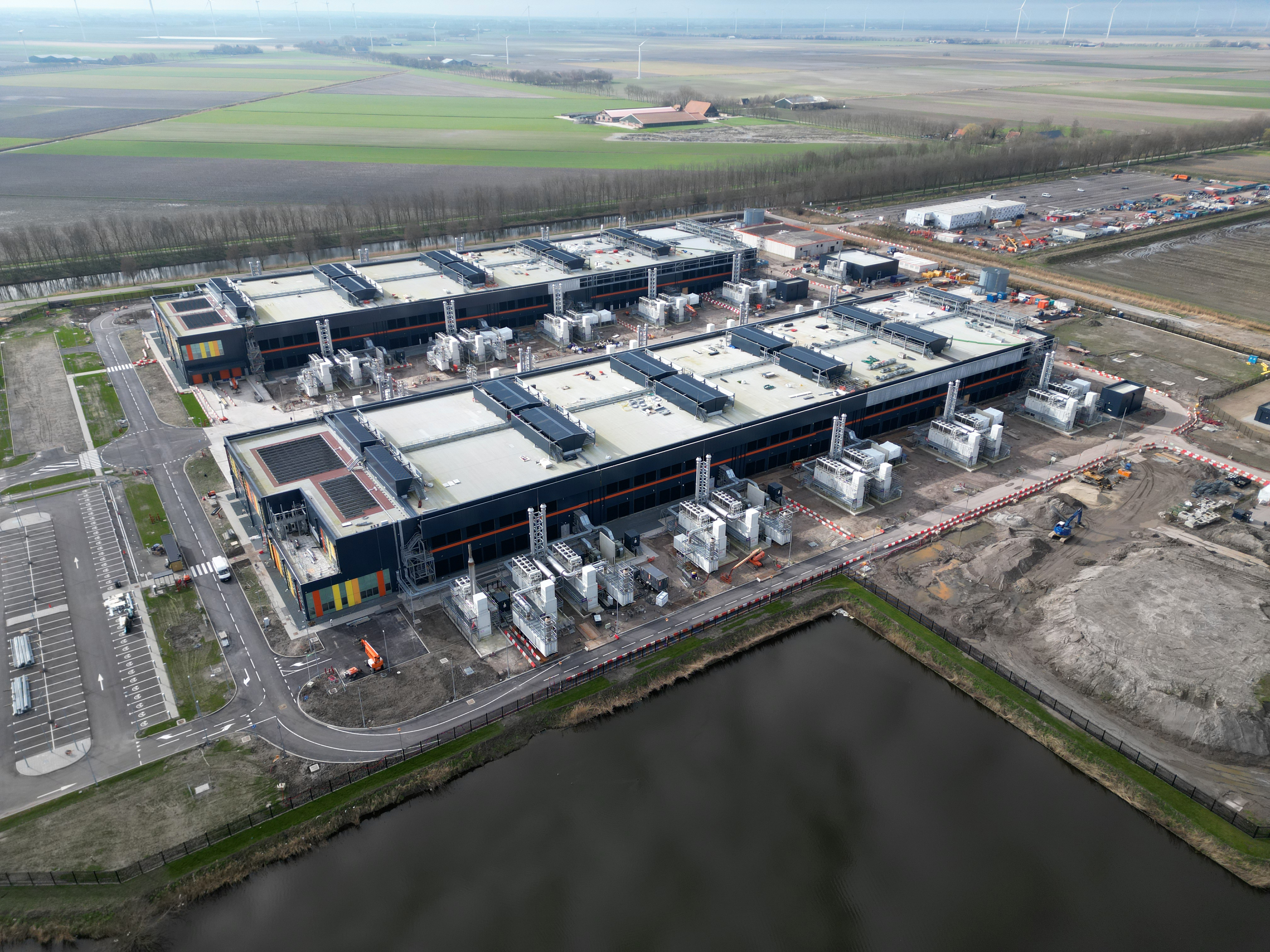 Grands entrepôts utilisés pour les centres de données à côté d'un grand plan d'eau.